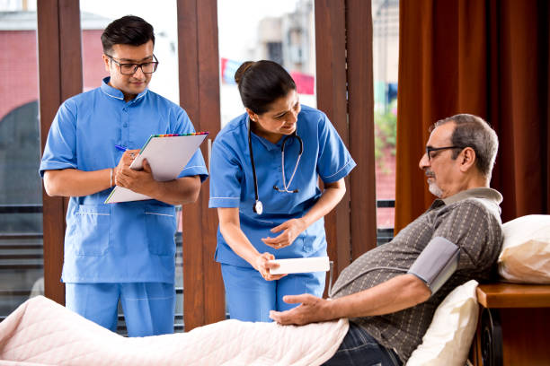 Nursing staff examining and making a note of senior patient's blood pressure reading